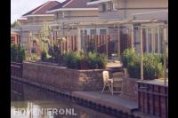 Tuin aan waterkan met vlonder en houten pergola's