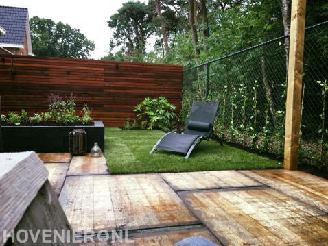 Tuin met houten schutting, gazon en plantenbak