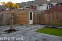 Achtertuin met bestrating van betontegels en kunstgras