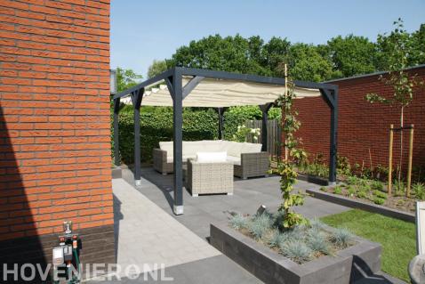 Houten pergola met harmonicadoek boven terras met loungeset