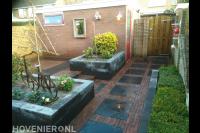 Achtertuin met plantenbakken en bestrating van klinkers en siertegels