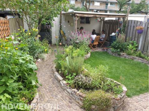 Kleine groene tuin met hergebruikte materialen voor terras en borders