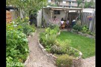 Kleine groene tuin met hergebruikte materialen voor terras en borders