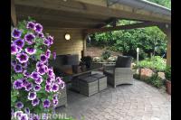 Houten overkapping met bestrating van koppelstenen en loungeset