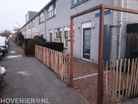 Kleine voortuin met verharding van schelpen, schapenhek en pergola