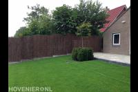 Strak groen gazon en schutting van heidematten