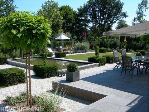 Moderne tuin met verhoogd terras, vijver en gazon 1