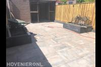 Achtertuin met natuursteen tegels en plantenbakken