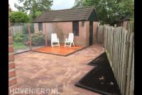 Kleine achtertuin met houten vlonder en bestrating van rode stenen