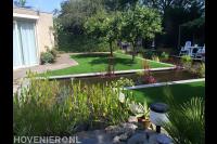 Tuin met grote vijver, kunstgras en fruitbomen