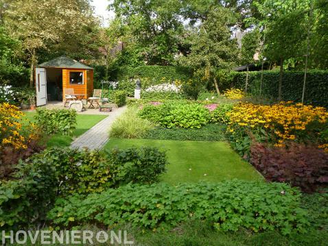 Natuurlijke tuin met tuinhuisje, gazon en kleurrijke bloemen