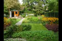 Natuurlijke tuin met tuinhuisje, gazon en kleurrijke bloemen