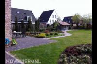 Open tuin met terras bij woning, gazon en tuinhuisje