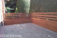 Tuin met bestrating van grindtegels en hardhouten schutting met poort