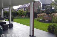 Tuin met terras van keramische tegels, gazon en kleine vijver