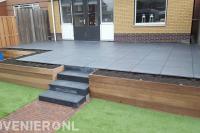 Verhoogd terras van siertegels met trappetje en houten beschoeiing