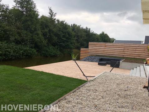 Tuin aan het water met houten vlonder en schutting