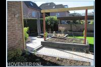 Houten pergola boven bloembak van stapelblokken