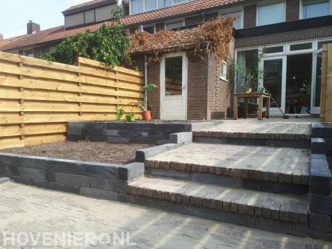 Plantenbakken en trappetje van klinkers in tuin met hoogteverschil