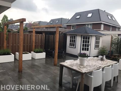 Moderne tuin met bestrating, houten pergola en witte bloembakken