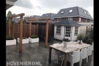 Moderne tuin met bestrating, houten pergola en witte bloembakken