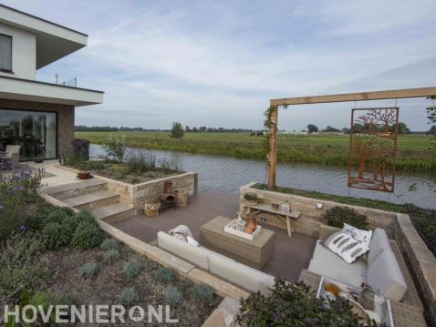 Zitkuil met pergola en vlonder in tuin aan het water