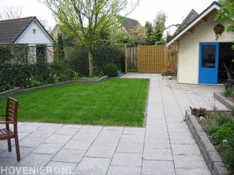 Achtertuin met gazon, tuinhuis en tuinafscheiding met klimop