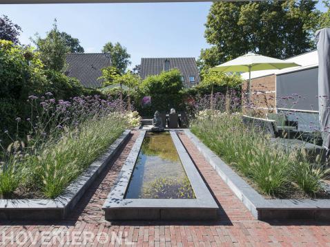 Tuin met strakke vijver en borders met siergras