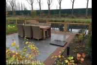 Terras met tuinmeubels en hekwerk aan waterkant