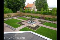 Ruime tuin met sierbestrating, gazon en houten schutting