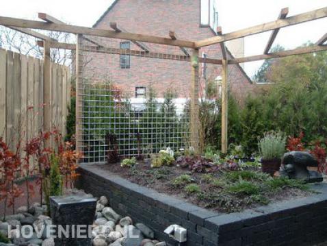 Pergola met wand van betongaas en verhoogde border van stapelblokken