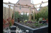 Pergola met wand van betongaas en verhoogde border van stapelblokken