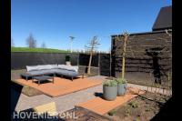 Tuinaanleg met bestrating, houten vlonder en loungeset