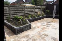 Verhoogde border van stapelblokken en bestrating van natuursteen