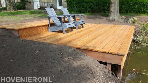 Houten vlonder met ligstoelen aan het water