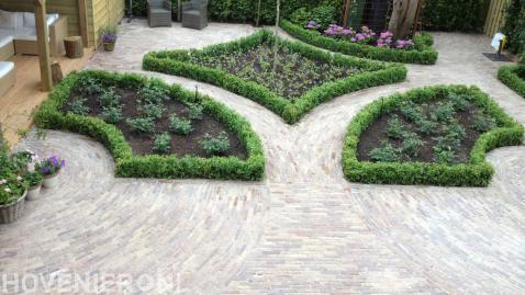 Tuinaanleg met vloeiende lijnen, oude stenen en buxus om borders