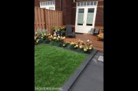 Achtertuin met kunstgras en houten vlonder