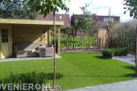 Houten tuinhuisje met overkapping en kunstgras gazon