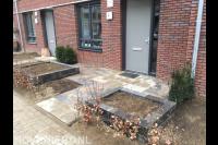 Kleine voortuin met bestrating, bloembakken en beukenhaag