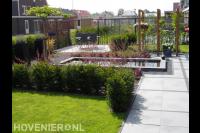 Moderne tuin met gazon, vijver en houten pergola