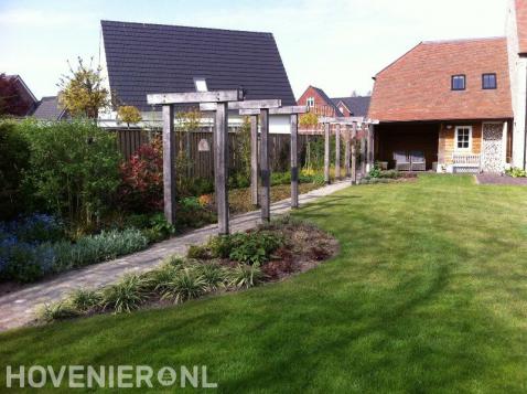 Houten pergola's boven tuinpad langs gazon 1