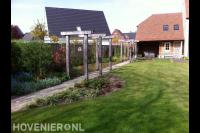Houten pergola's boven tuinpad langs gazon 1