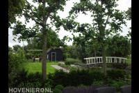 Tuin aan het water met groot gazon en veel groen