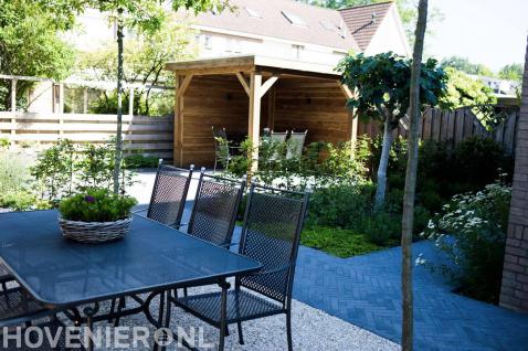 Achtertuin met houten overkapping en zitplek met grind