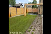 Tuinaanleg met gazon, houten pergola, schutting en trampoline