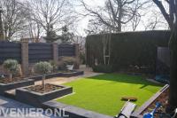Achtertuin met terras, kunstgras en borders van stapelblokken