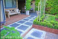 Achtertuin met bestrating, houten vlonder en plantenbakken