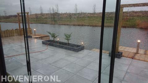 Tuin aan het water met terras en houten pergola's