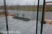 Tuin aan het water met terras en houten pergola's