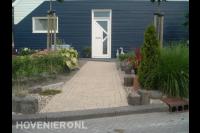 Voortuin met looppad van lichtbruine klinkers en kleurrijke beplanting